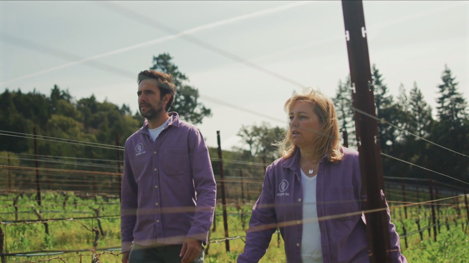 Founders Martin García Wilhelm and Kristi Bowers walking through a vineyard in Grape.ag shirts, in a still from the brand video